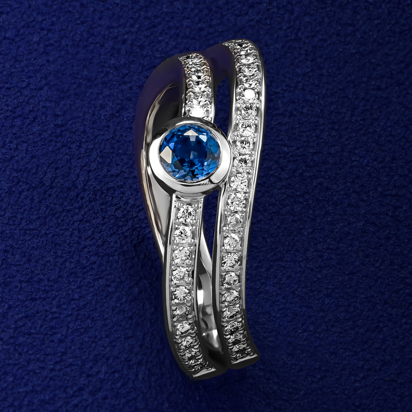 Double Wavy Ring with a royal blue sapphire in the middle and diamonds set in pave , iconic design by carati jewelry in montreal canada in 18k 14k in blue backround and zoomed