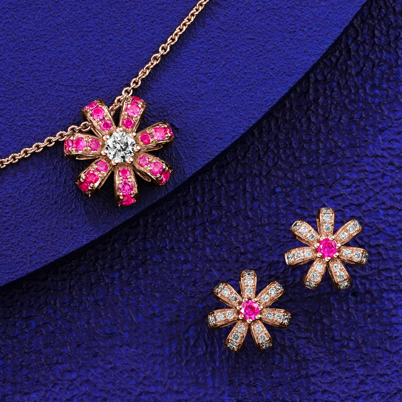 A pair of rose gold Fiora earrings with natural ruby centers and encrusted with diamonds set in pave designed by carati jewelry montreal canada 18k 14 k in blue backround with the pendant