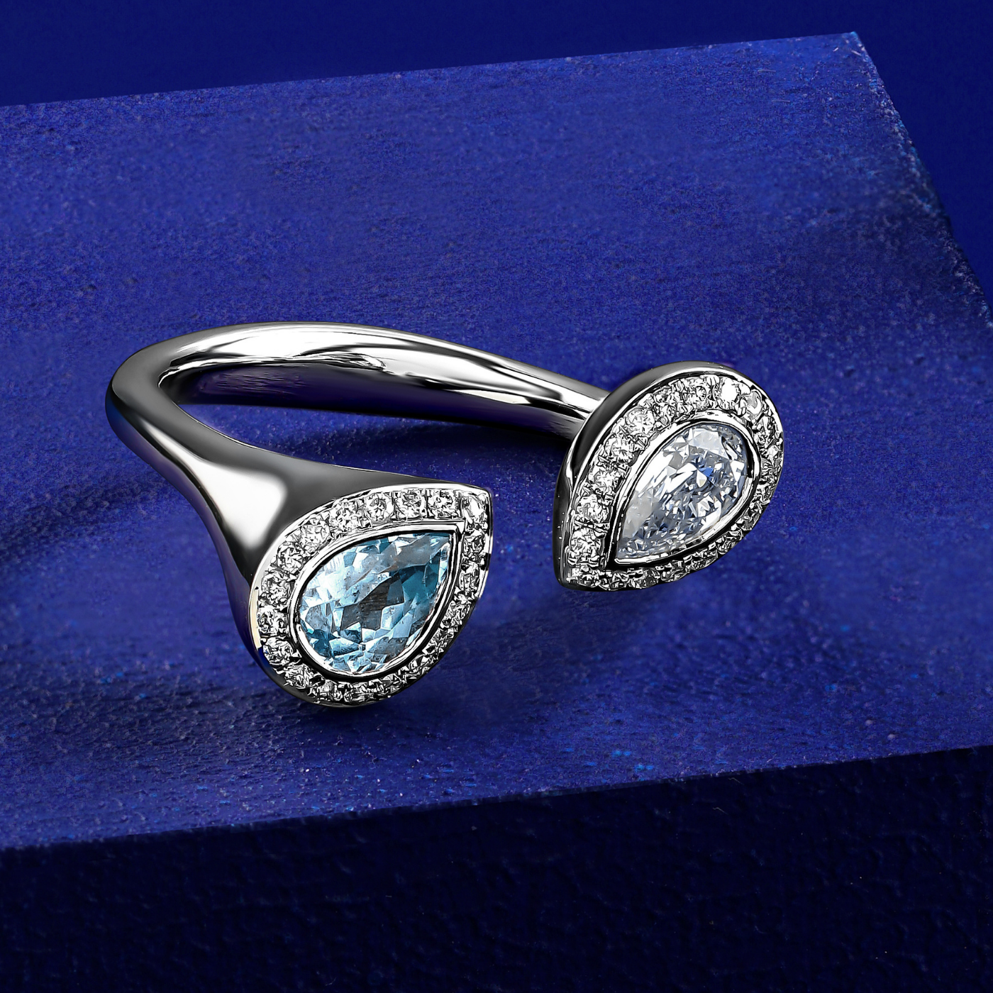 Toi et moi reimagined with pear aquamarine and diamond surrounded by pave set diamonds designed by carati jewelry montreal canada 14 k 18 k in blue backround