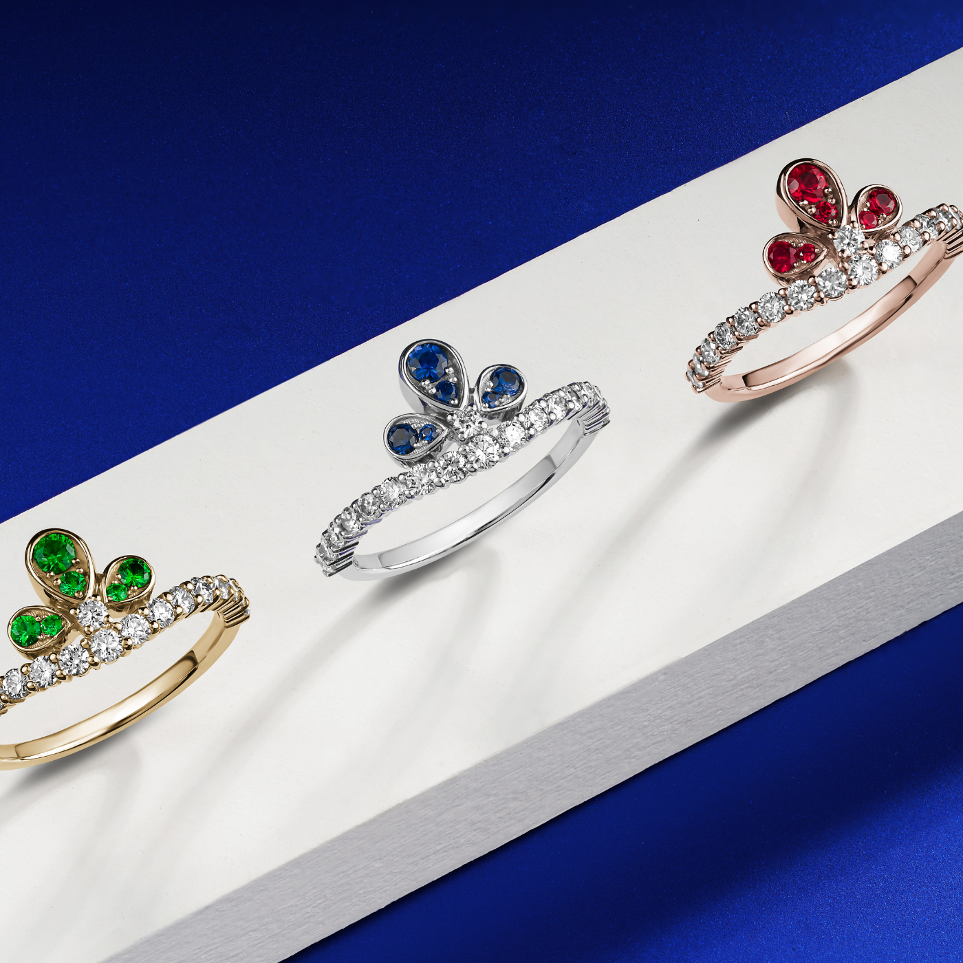 Bloom ring set with a rubys and diamonds going half way designined by carati jewelry montreal canada 18 k 14 k with blue backround with 3 rings