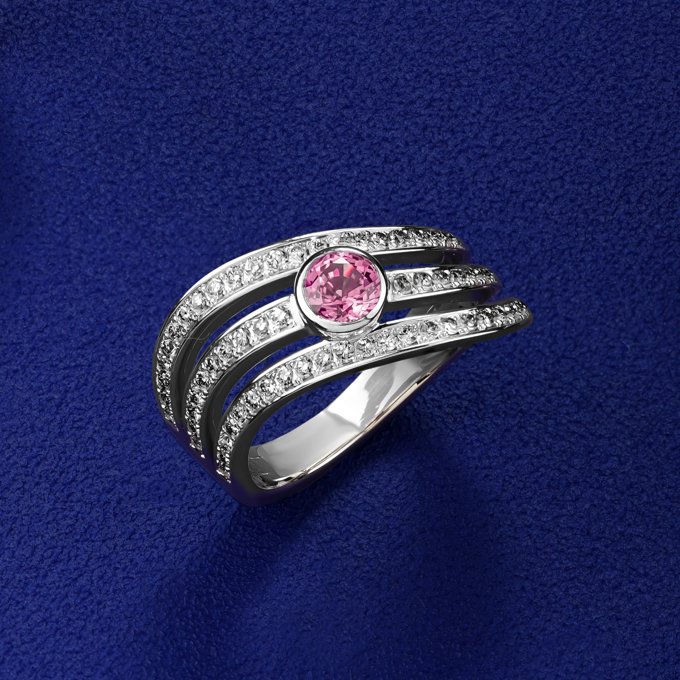 triple wavy design with a centered pink sapphire set ,and diamonds pave set all around designed by carati jewelry in montreal canada in 18 k 14 k in blue backround
