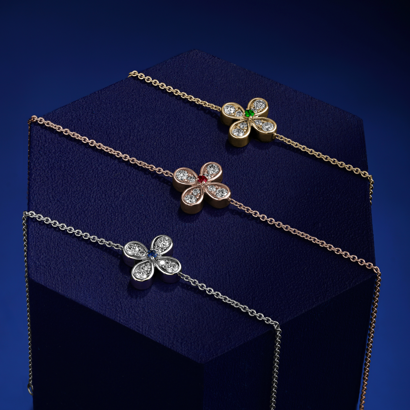 in blue backround and top of a piece Bloom bracelets with a floral charm featuring a blue sapphire center and small diamond accents designed by carati jewelry in montreal canada in 18 k 14 k