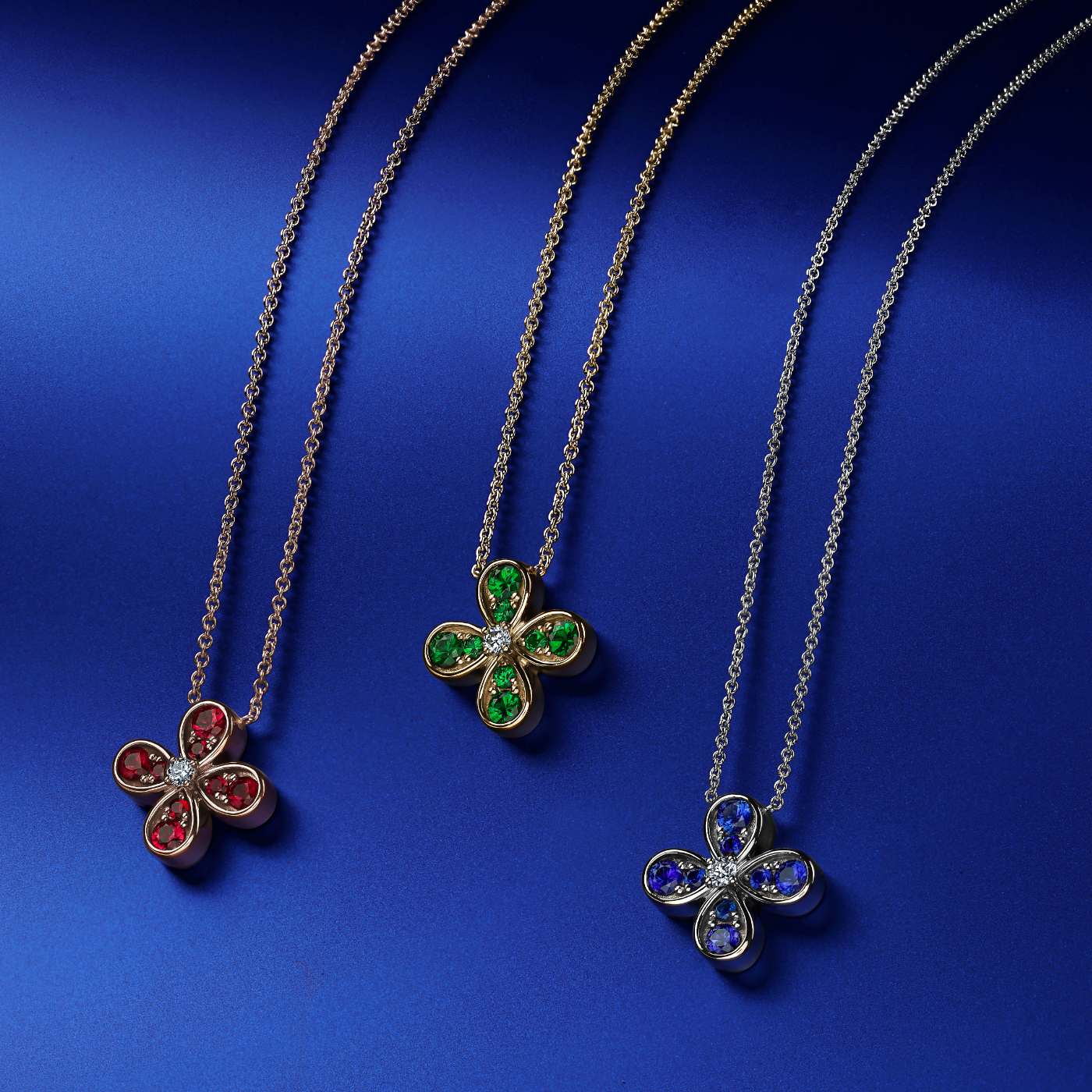 Bloom pendant set in ruby's and a diamond in the middle designed by carati jewelry montreal canada 18k 14 k in blue backround with all 3 pendants