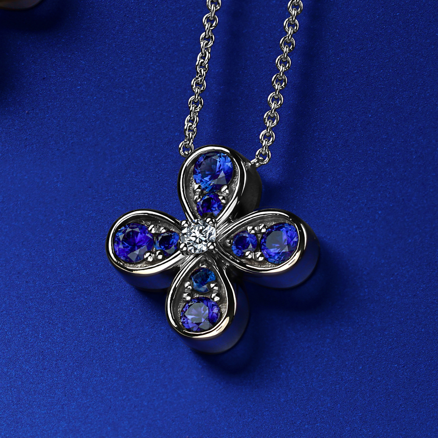 Bloom pendant set in royal blue sapphires and a diamond in the middle designed by carati jewelry montreal canada 18k 14 k in blue backround and zoom