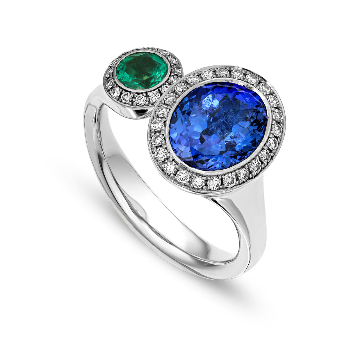 Toi et moi ring featuring an oval-shaped tanzanite and a round emerald surrounded by smaller diamonds sophisticated spark designed by carati jewelry in montreal canada in 18 k 14 k