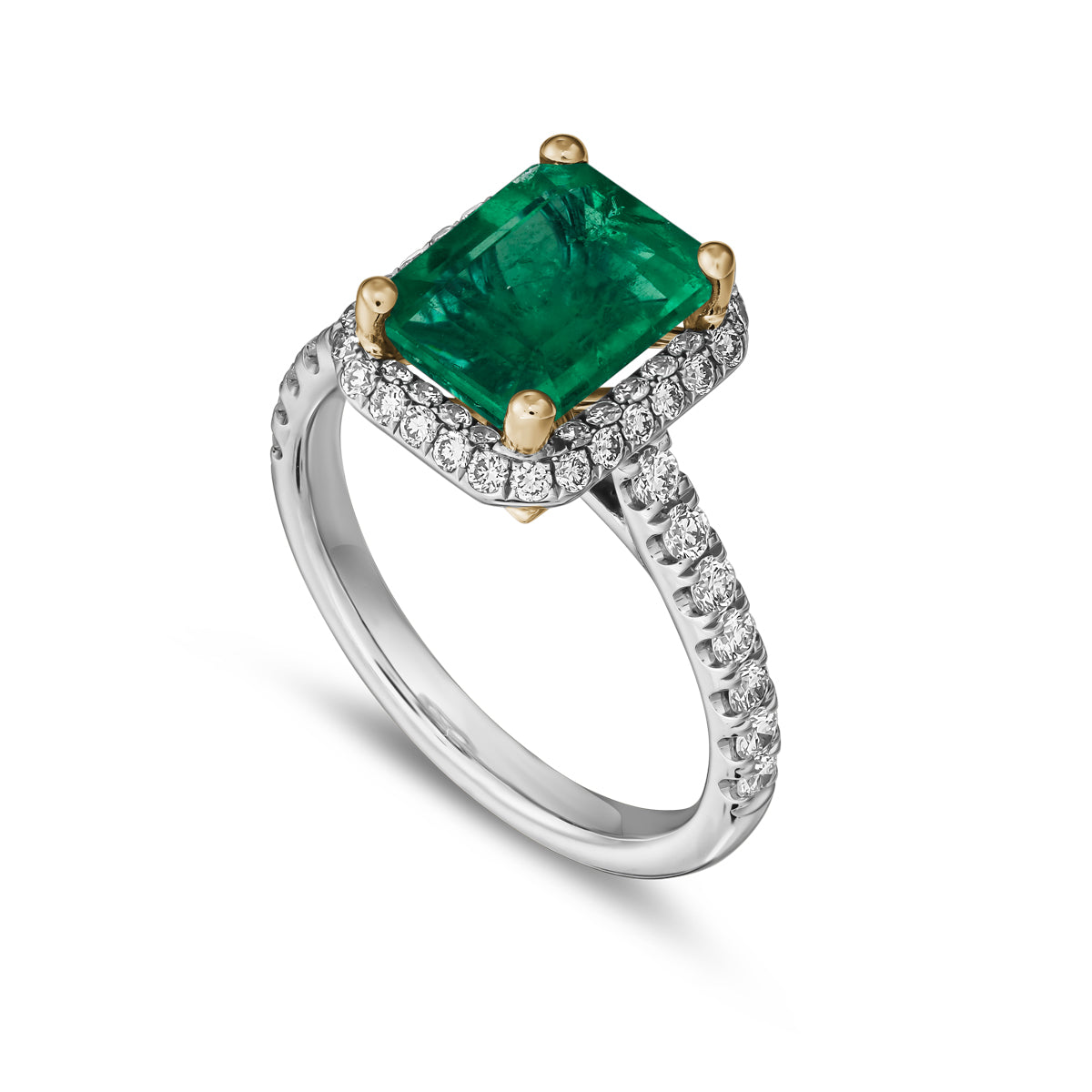 A two-tone gold ring featuring a radiant cut emerald gemstone with a halo of pave set diamonds around it designed by carati jewelry montreal canada 18 k 14 k
