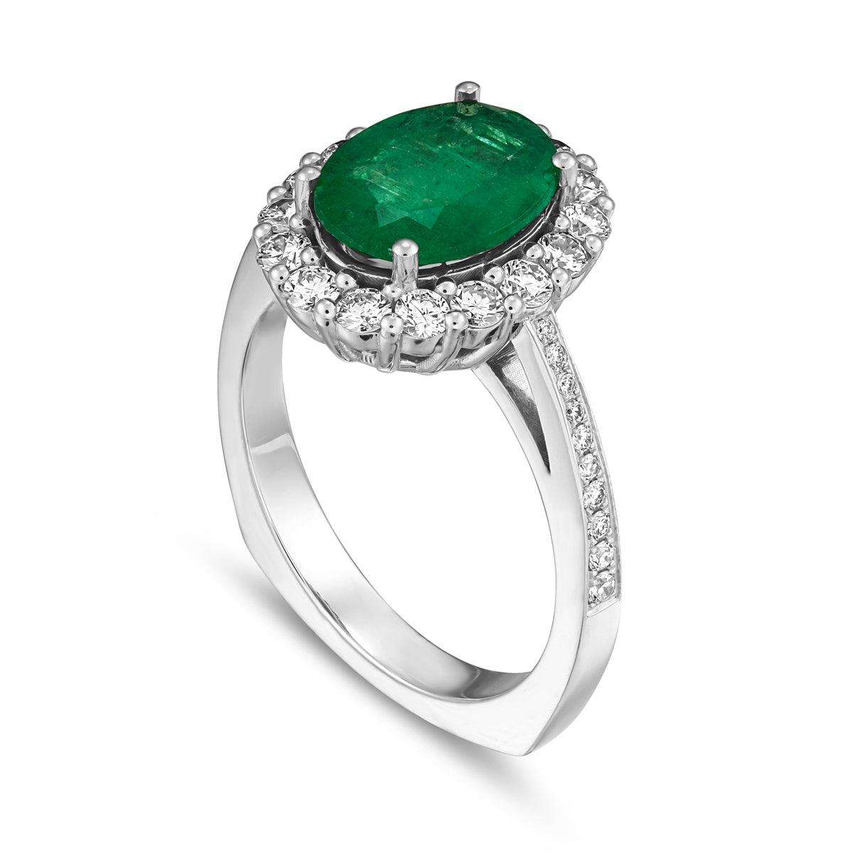 An oval emerald engagement ring with a halo of round diamonds around it and on the band, set in a white gold metal designed by carati jewelry montreal canada in 18k 14 k