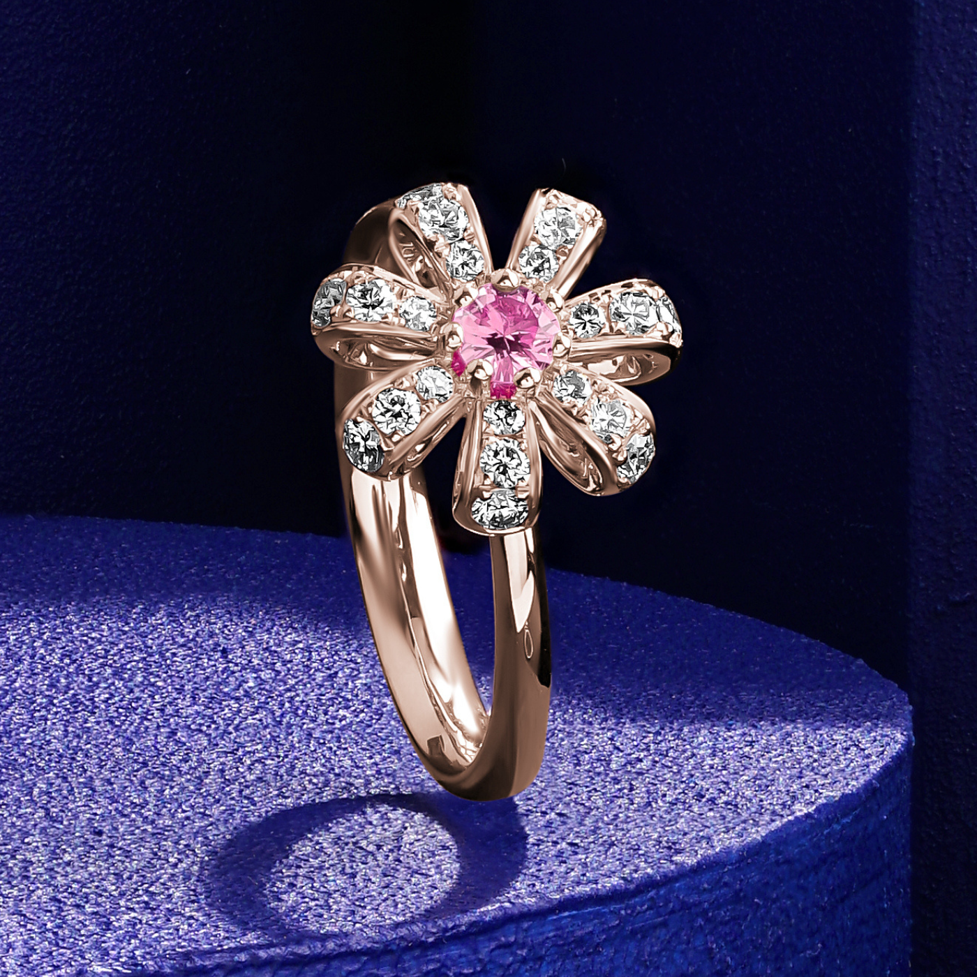 Fiora Ring set in pave Diamonds and a Sparkling Pink Sapphire in the middle is iconic design from carati jewelry in montreal canada in 18k 14 k with blue backround 