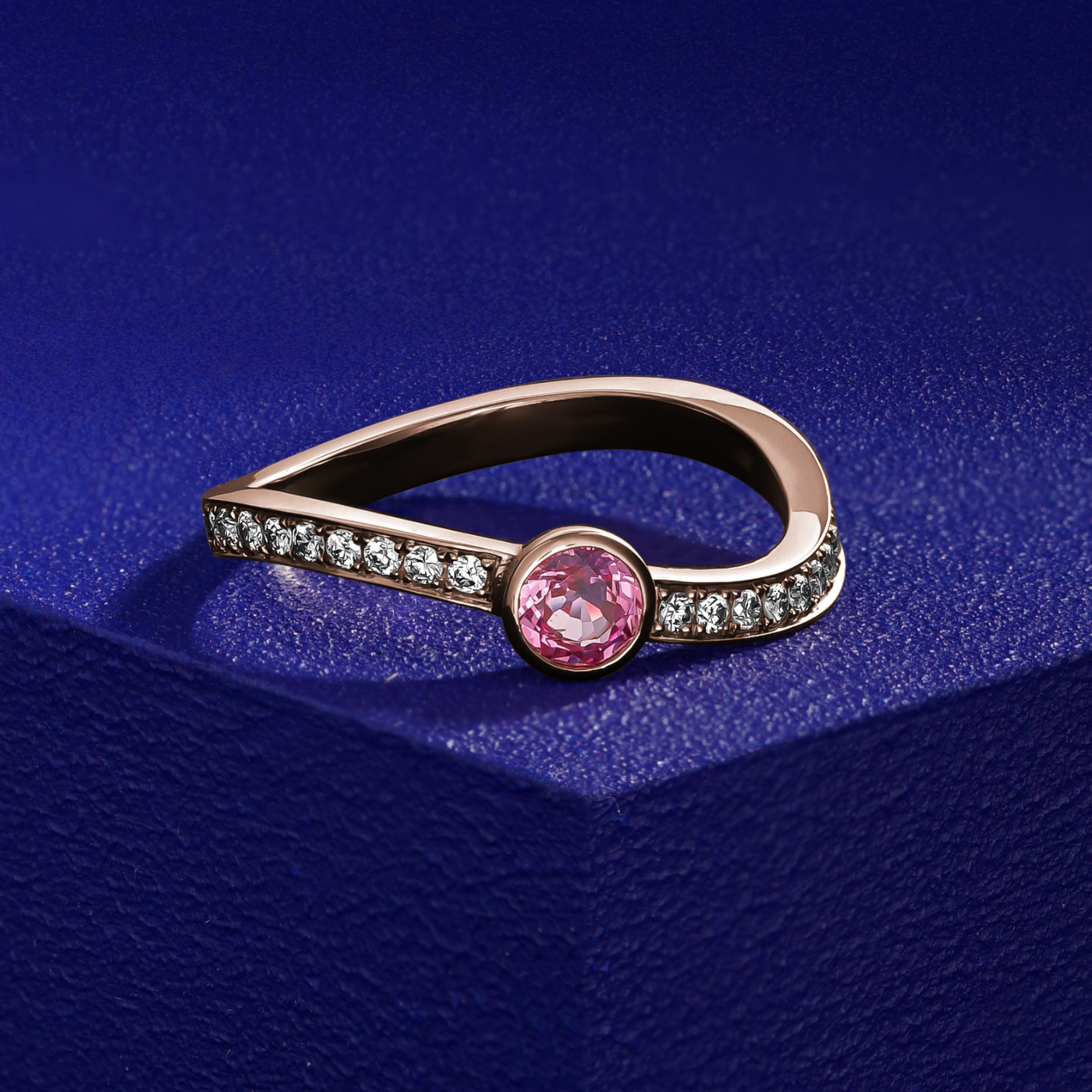 single Wavy Ring with a pink sapphire in the middle and diamonds set in pave , iconic design by carati jewelry in montreal canada in 18k 14k with blue backround and zoomed