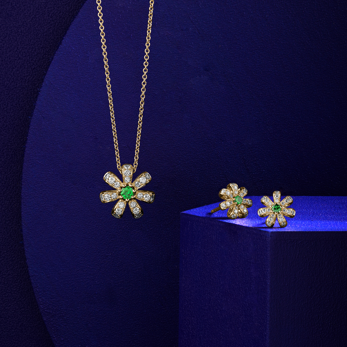 A pair of  Fiora earrings with naturaln tsavorites centers and encrusted with diamonds set in pave designed by carati jewelry montreal canada 18k 14 k  with blue backround and pendant