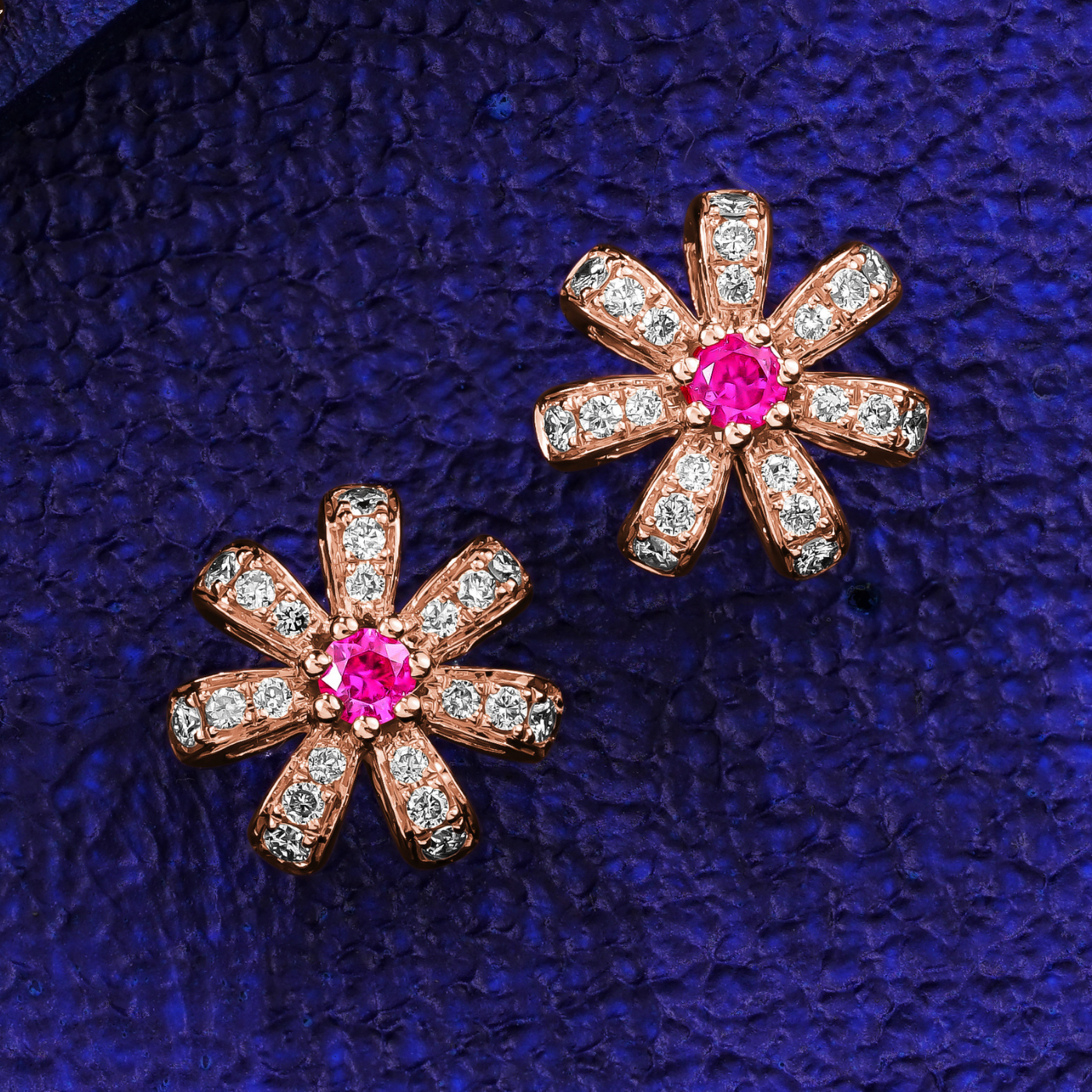 A pair of rose gold Fiora earrings with natural ruby centers and encrusted with diamonds set in pave designed by carati jewelry montreal canada 18k 14 k  in blue backround and zoom