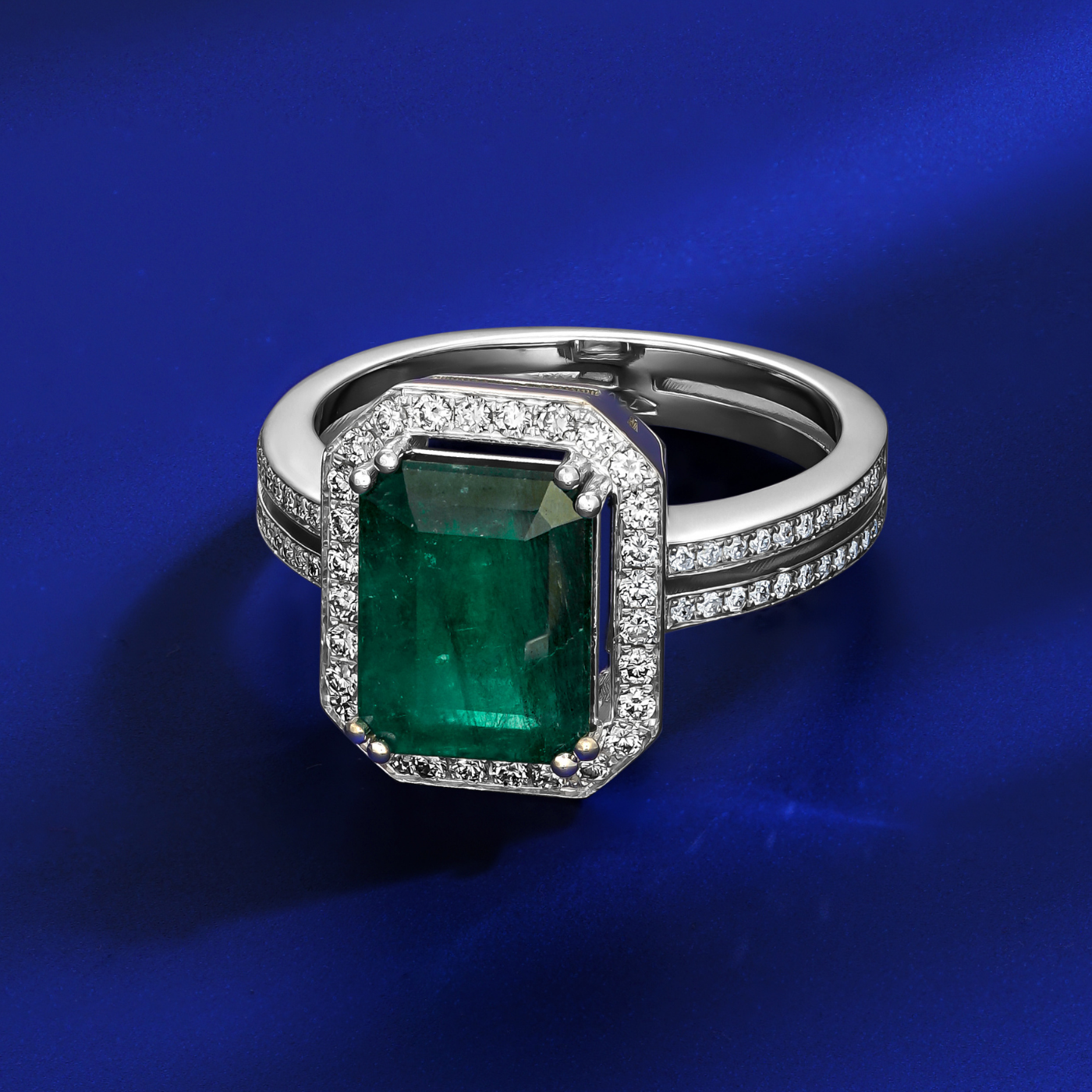 in blue backround An emerald cut diamond engagement ring with parallel shank and smaller diamonds around it, set in a likely white gold or platinum band designed ny carati jewelry in 14 k 18 k 