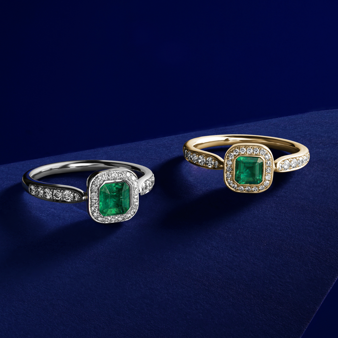 Royal harmony ring with tie emerald surrounded by pave diamonds and on the shank designed by carati jewelry in montreal canada 18k 14 k in blue backround and another ring