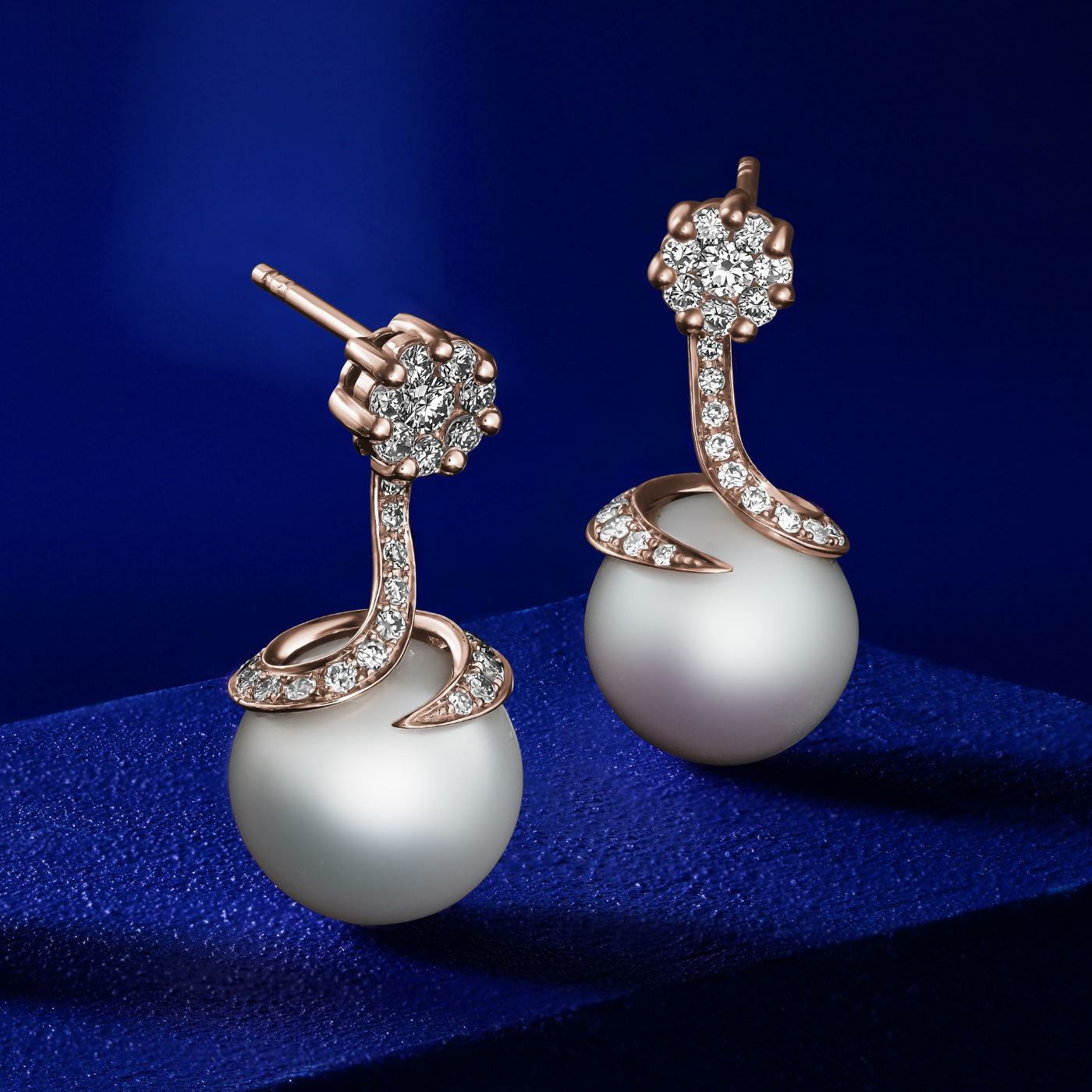 Spirale earrings with natural south sea pearl with pave set diamonds in spirale design ,designed by carati jewelry montreal canada 18 k 14 k in blue backround
