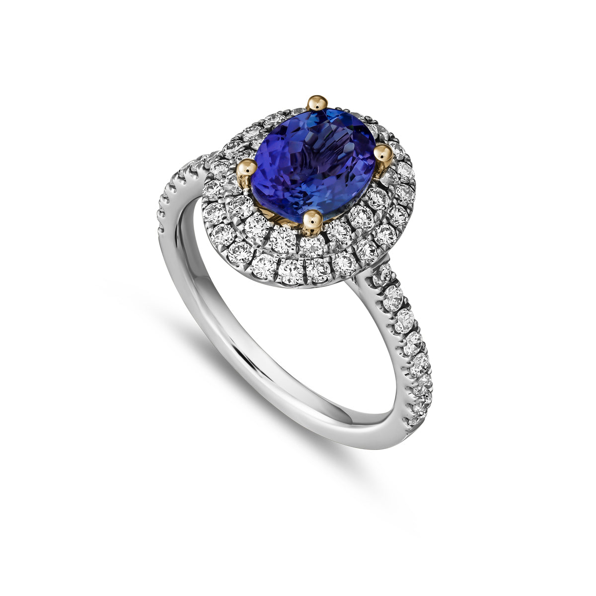 A two row two tone halo ring centered with a oval-shaped tanzanite stone and surrounded by smaller diamonds set in a silver or white gold band from carati jewelry montreal canada two tone yellow and white gold 14 k 18 k