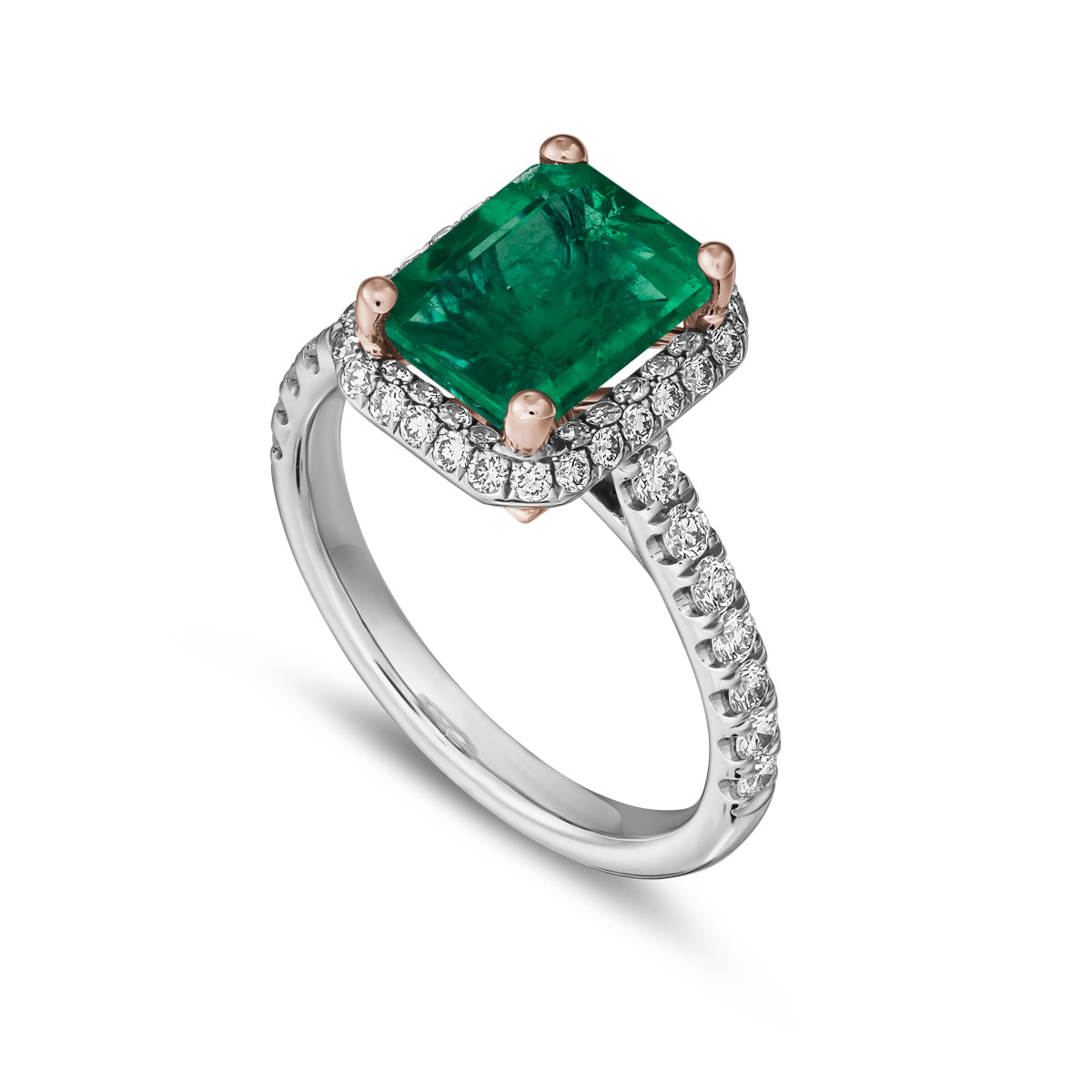 A two-tone gold ring featuring a radiant cut emerald gemstone with a halo of pave set diamonds around it designed by carati jewelry montreal canada 18 k 14 k